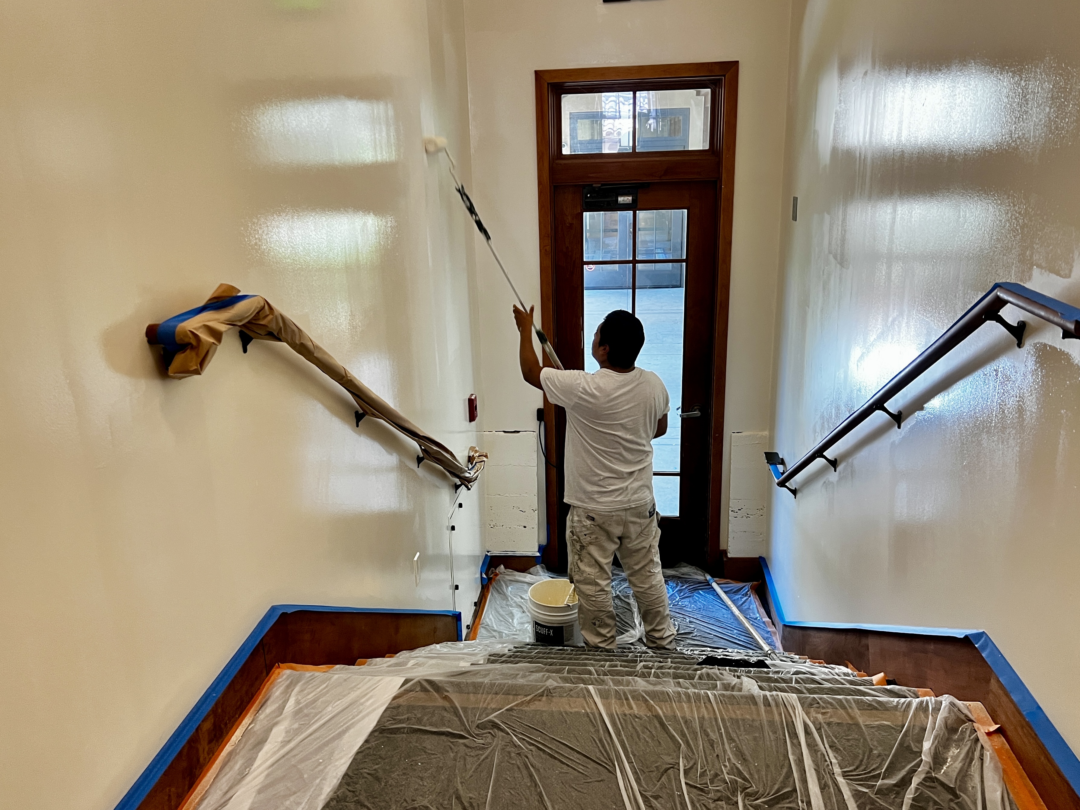Chay & Harris painter rolling stairwell walls with extension pole